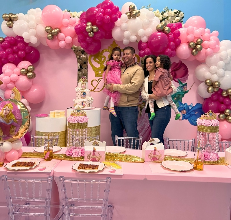 Happy family celebrating a kids birthday with a Cinderella party theme and beautiful balloon garland at Kidz Kastle private venue in Warwick, RI.